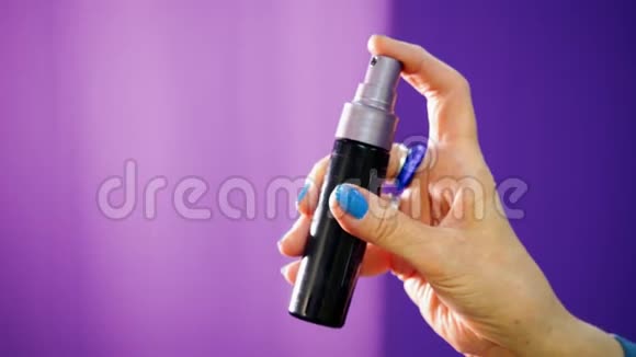 女人她手里拿着喷雾瓶正在紫色的背景上喷洒一些东西视频的预览图