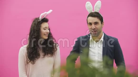 年轻夫妇站在粉红色的背景上在这段时间里他们一起看着相机说话真诚的微笑视频的预览图