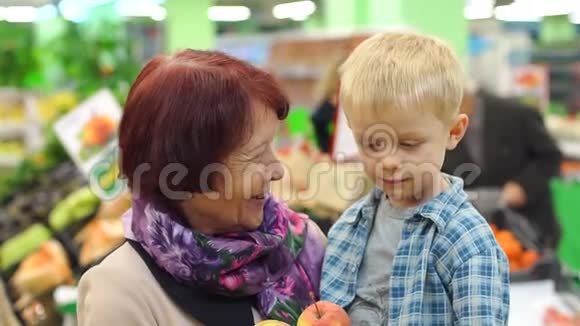 祖母和她的小孙子在一家大型超市买新鲜苹果视频的预览图
