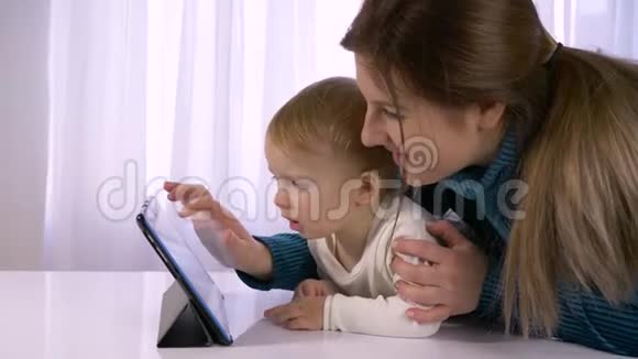 家庭关系中的现代科技幸福的孩子和妈妈在明亮的房间里玩平板电脑视频的预览图