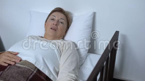 生病的老年女性病人躺在病床上几乎没有呼吸也没有寻求帮助视频的预览图