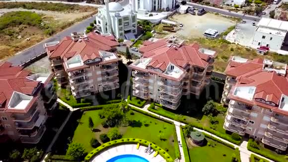 清真寺附近的酒店剪辑以白色清真寺为背景的带有新酒店和游泳池的度假建筑群的俯视图视频的预览图