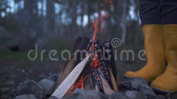 人的双腿穿着黄色的橡胶靴站在森林里燃烧的火堆附近视频的预览图