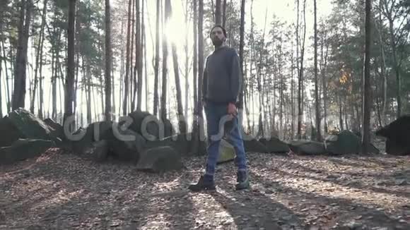 站在森林里的大胡子把一把斧子放在肩上在森林里长着一把斧头的英俊野蛮的无胡子家伙视频的预览图