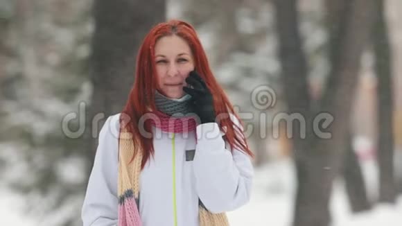 冬季公园一个红头发的女人在电话里说话一场大雪肖像视频的预览图