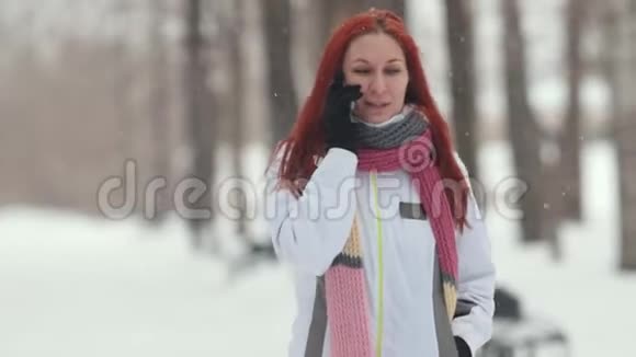 冬季公园一个红头发的女人在电话里说话一场大雪关门视频的预览图
