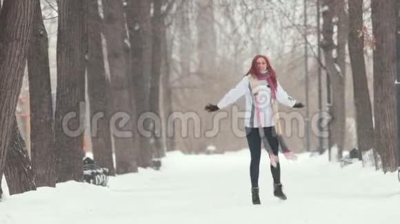 冬季公园站在人行道上的一个红头发的女人做跳跃之类的活动视频的预览图