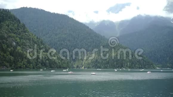 在一个充满活力的阴天夏季阿布哈兹山的高山湖景观双体船在山上的湖面上漂浮视频的预览图