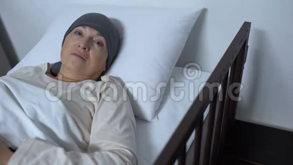 患癌症的无助女性病人躺在病床上看着摄像机视频的预览图