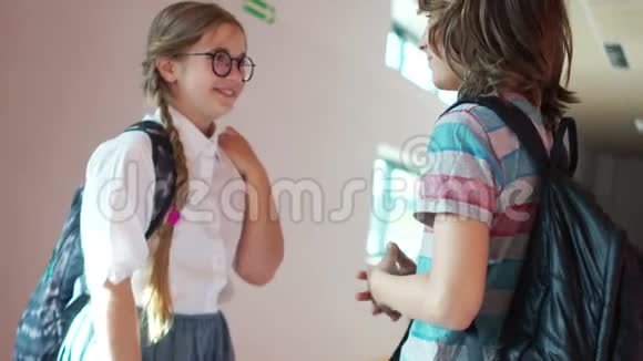 休息时两个朋友在学校走廊里聊天女孩穿着白色衬衫戴着眼镜扎着可爱的辫子视频的预览图