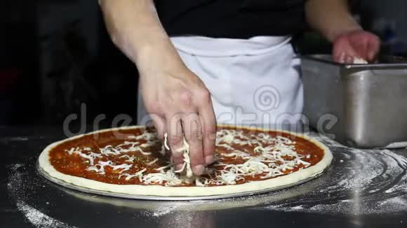 厨师在比萨饼店准备比萨饼时把磨碎的奶酪放在面团上视频的预览图