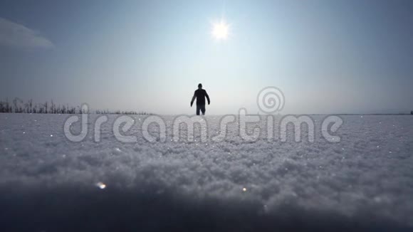 人在镜头前在天空中做一个步伐一个孤独的人走在雪地里一个人在雪地里行走的戏剧性轮廓视频的预览图