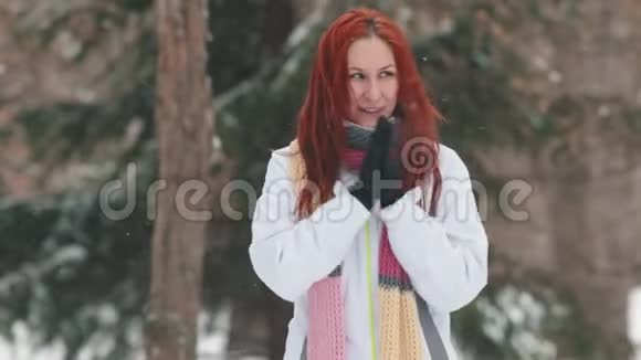 冬季公园一个有着鲜红头发的开朗的女人试图温暖她的双手视频的预览图