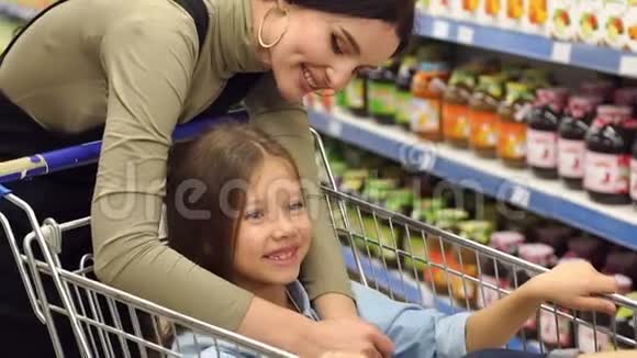 一个小女孩坐在超市的购物车里妈妈拥抱了她视频的预览图