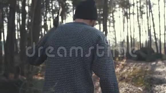 长胡子的人肩上扛着斧子走在博蒂尔森林里在户外用斧头做的视频的预览图