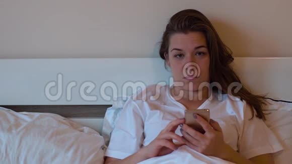 女人用智能手机躺在床上视频的预览图