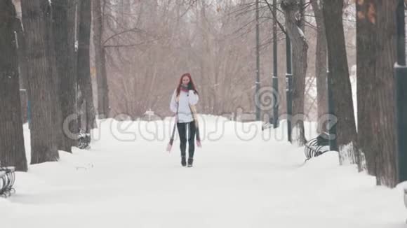冬季公园一个留着鲜红头发的女人在打电话一场大雪坏天气视频的预览图