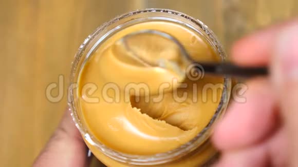 与勺子花生酱混合奶油软面花生酱在罐子背景视频的预览图