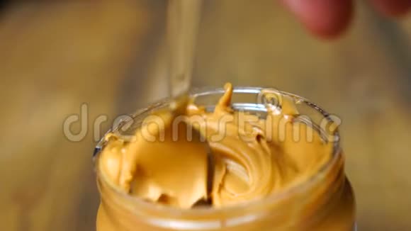 奶油光滑花生酱在罐子背景与勺子花生酱混合视频的预览图