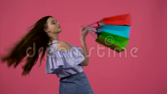带着购物袋的女孩站在那里她的背转过身眨着眼睛粉色背景视频的预览图