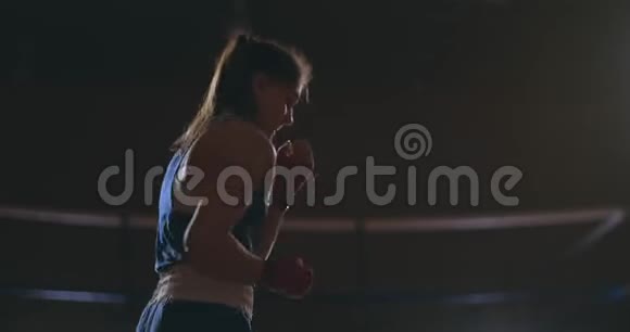 一个漂亮的女拳击手在一个黑暗的大厅里进行暗斗时卸下了打击视频的预览图