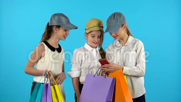 三个青少年用五颜六色的包裹做自拍蓝色背景视频的预览图