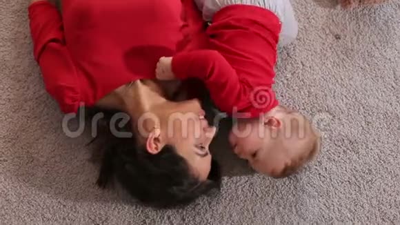 俯视着躺在蓬松地毯上的年轻女子和她的小儿子视频的预览图