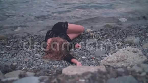 一个年轻的女孩躺在海边没有知觉没有动作那个女人面朝下躺在岸上视频的预览图