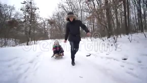 白雪森林里的幸福家庭爸爸在冬天拉着儿子和女儿的雪橇视频的预览图