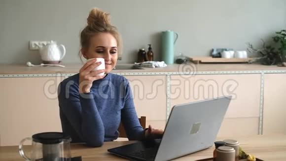 年轻的女人拿着一张桌子在笔记本电脑上工作靠近她的手和饮料视频的预览图