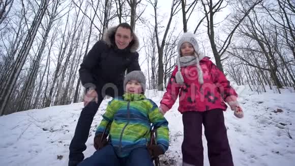 在冬天的周末孩子们和爸爸一起玩在雪地森林里跑步和滑雪视频的预览图