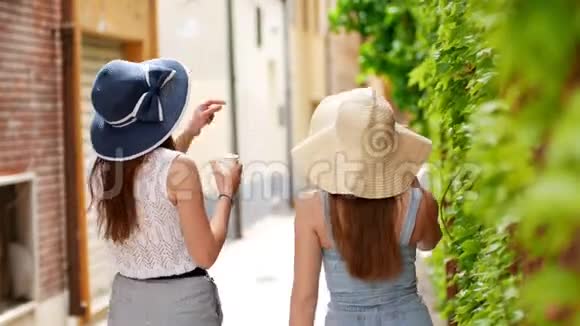 两个穿着睡衣的年轻女子沿着绿墙走在城市的大街上视频的预览图