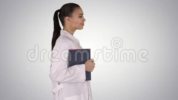 幸福微笑的女医生走着拿着笔记本或文件在梯度背景上视频的预览图