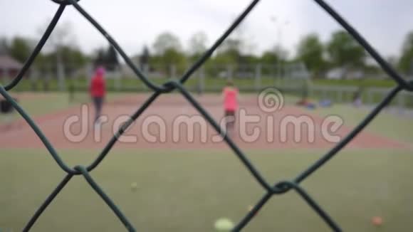 母亲和女儿在网球场上打网球网背景运动复印空间视频的预览图