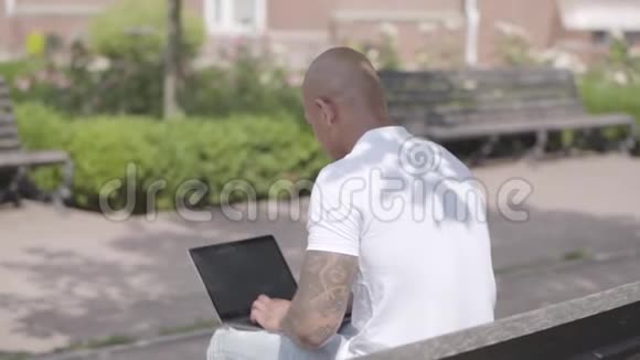 英俊的秃顶的中东商人手提电脑坐在街上的长凳上自由职业概念男子视频的预览图