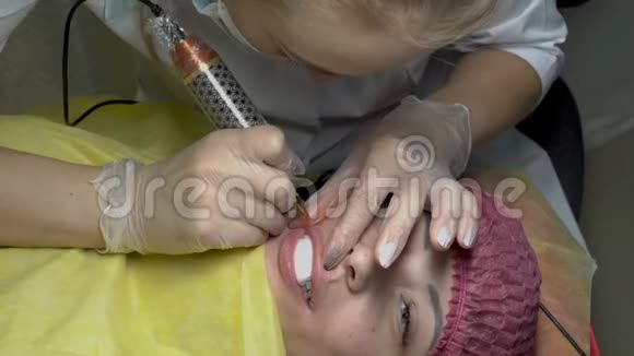 嘴唇永久性化妆的化妆程序女人化妆师用一根针涂在女孩嘴唇上视频的预览图