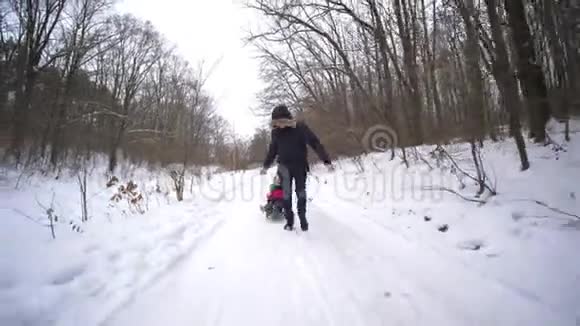 家庭假日父亲在冬天的公园森林里拉着快乐的儿子和女儿视频的预览图