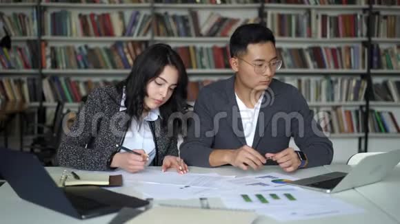 亚洲年轻夫妇男女在图书馆工作视频的预览图