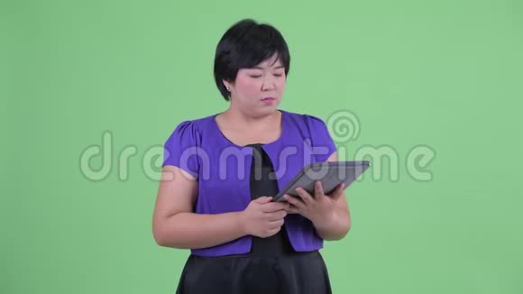 快乐年轻体重超重的亚洲女性使用数码平板电脑思考视频的预览图