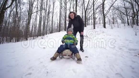 父子俩坐在雪山上的雪橇上在森林里休息视频的预览图