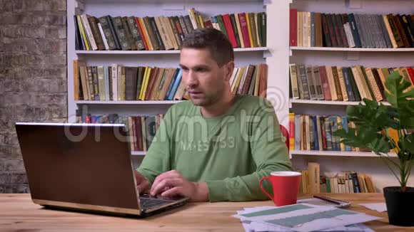 坐在笔记本电脑前的办公室工作人员对错误的失败感到紧张和压力书架上的书架视频的预览图
