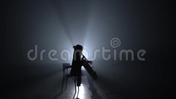 女人晚上在烟雾弥漫的房间里鞠躬大提琴剪影黑烟背景视频的预览图