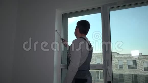 专业画家用手辊在窗户附近画墙边视频的预览图