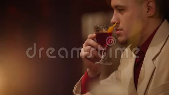 迷人的男人正在酒吧里闻着红色的利口酒里面有柔和的灯光视频的预览图