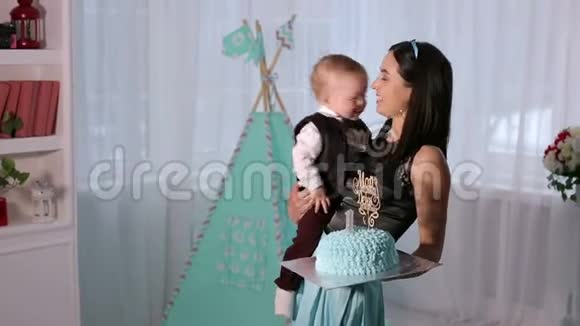 一个快乐的母亲和一个一岁的儿子在生日时带着蛋糕的肖像视频的预览图