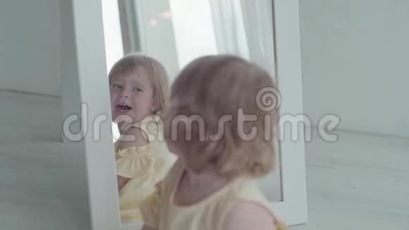 金发三岁的婴儿在家里摆姿势和看镜子慢动作视频的预览图