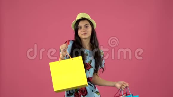 女孩手里拿着五颜六色的包裹跳舞粉色背景慢动作视频的预览图