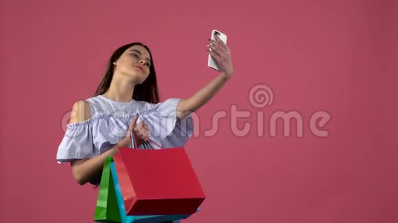 女孩用五颜六色的包裹做自拍粉色背景慢动作视频的预览图