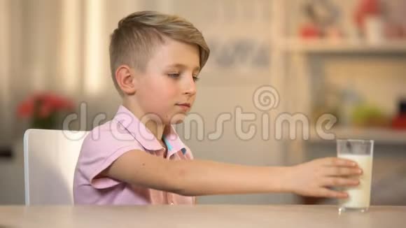 男孩从桌子上的玻璃中喝新鲜的有机牛奶早晨能源食品奶制品视频的预览图