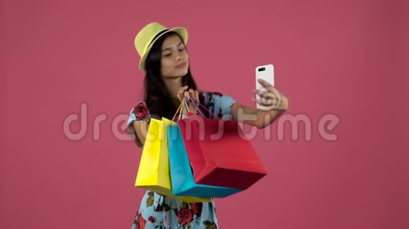 青少年用五颜六色的包裹做自拍粉色背景慢动作视频的预览图